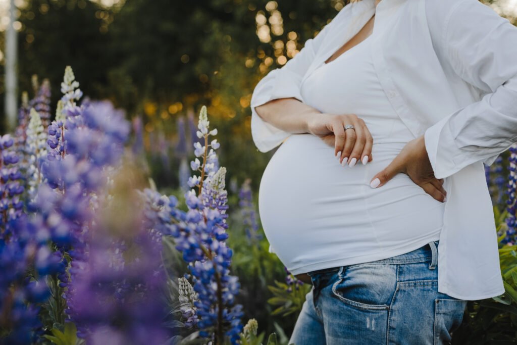 pregnant-woman-s-belly-close-up-without-her-face-lupines-field-scaled.jpg