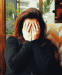 A lady sitting on the sofa putting her hands on her face.