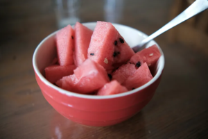 watermelon in a red bowl with a fork in it.