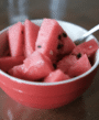 watermelon in a red bowl with a fork in it.