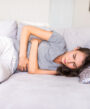 a woman lying down on sofa with menstrual cramps.